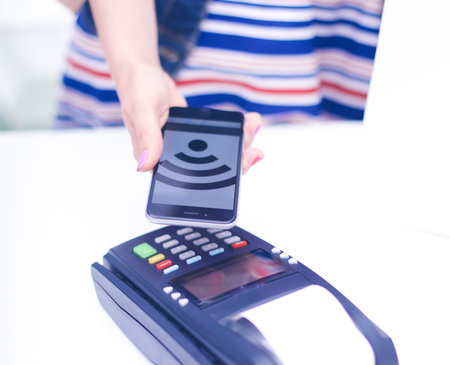 Customer is paying with smartphone in shop using NFC technology. NFC technology. Customer is paying