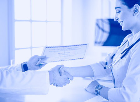 Doctor shakes hands with a patient isolated on white background