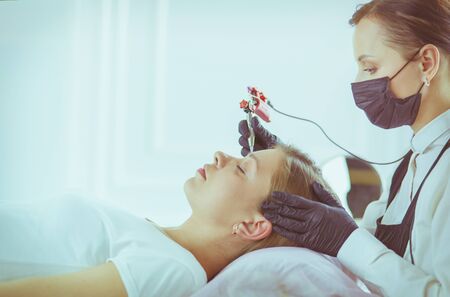 Young woman undergoing procedure of eyebrow permanent makeup in beauty salon.の写真素材