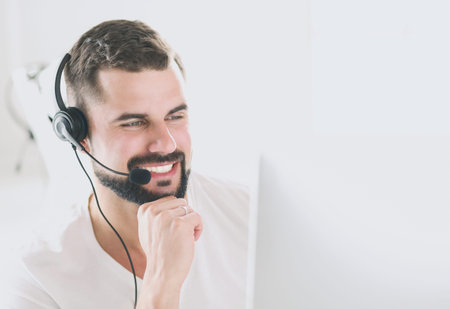 Portrait of a young man with a headset in front of a laptop computer