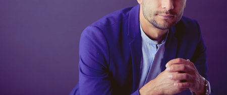Young businessman sitting isolated on grey background.