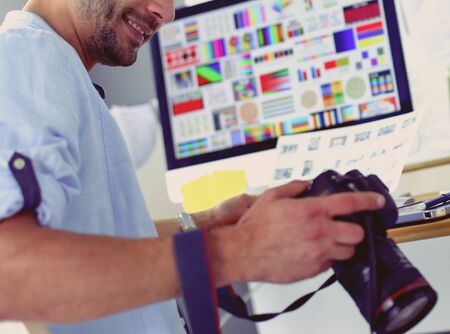Portrait of young designer sitting at graphic studio in front of laptop and computer while working online.の写真素材