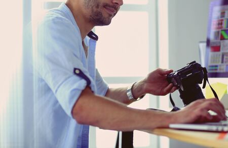 Portrait of young designer sitting at graphic studio in front of laptop and computer while working online.の写真素材