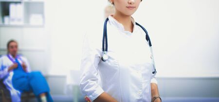 Young woman doctor standing at hospital with medical stethoscope.の写真素材