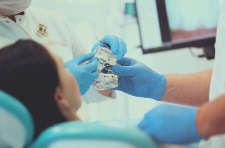 Senior male dentist in dental office talking with female patient and preparing for treatmentの写真素材