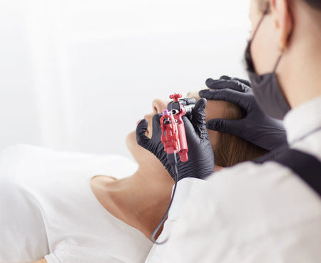 Young woman undergoing procedure of eyebrow permanent makeup in beauty salon.の写真素材