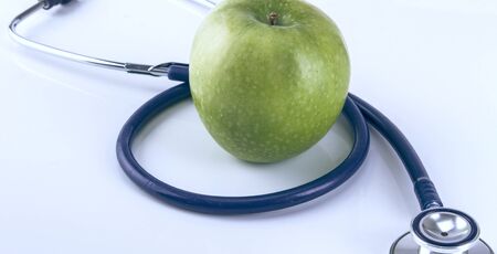 Medical stethoscope and apple isolated on white background.の写真素材
