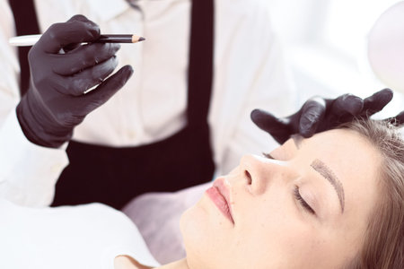 Cosmetologist applying permanent make up on eyebrows.