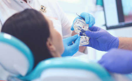 Senior male dentist in dental office talking with female patient and preparing for treatment.の写真素材