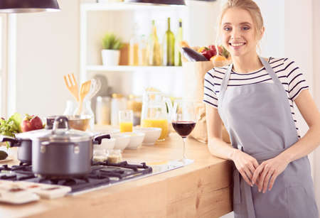 Pretty woman drinking some wine at home in kitchenの写真素材