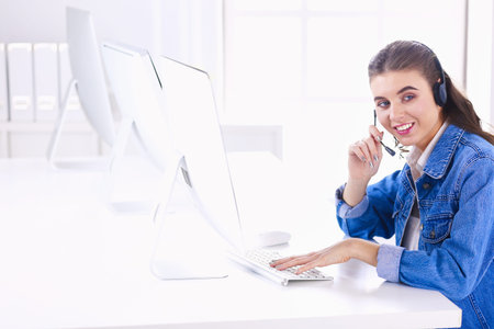 Smiling businesswoman with headset using laptop at the desk in work