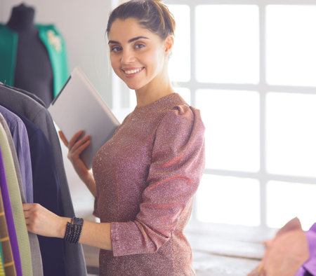 Beautiful young stylist near rack with hangers
