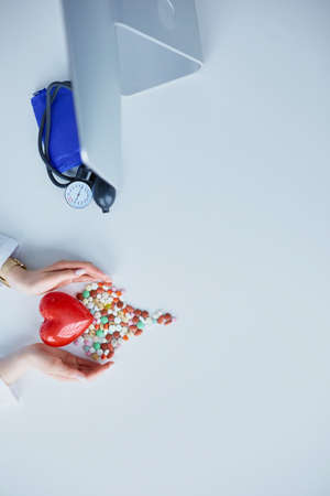 Cardiologist with red heart and stethoscope at tableの写真素材