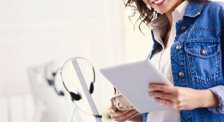 Smiling woman drinking coffee and using tablet in the cafeの写真素材