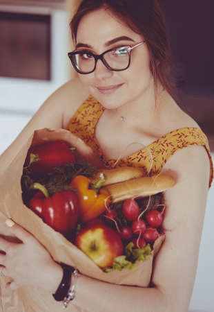 Young woman holding grocery shopping bag with vegetablesの写真素材