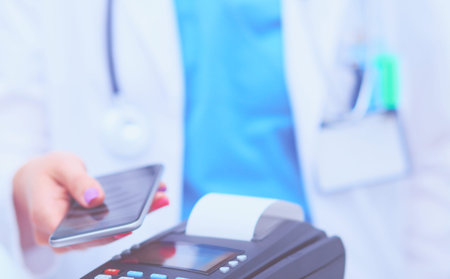 Doctor is holding payment terminal in hands. Paying for health care. Doctor