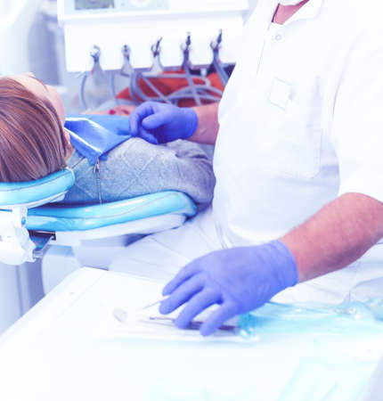 Senior male dentist in dental office talking with female patient and preparing for treatmentの写真素材