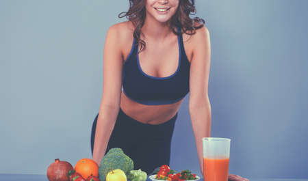 Young and beautiful woman standing near desk with vegetablesの写真素材