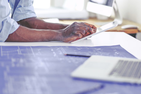 African american architect working with computer and blueprints in officeの写真素材
