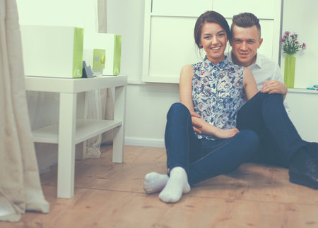 Happy young couple sitting together on the floorの写真素材