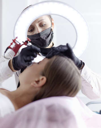 Microblading eyebrows work flow in a beauty salon. Woman having her eye brows tintedの写真素材