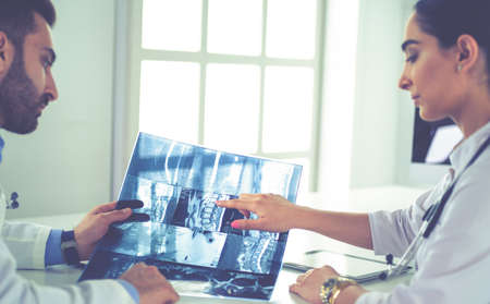 Two doctors studying x-ray image, consulting in bright officeの写真素材
