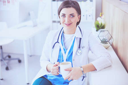Portrait of professional female doctor holding cup of coffeeの写真素材