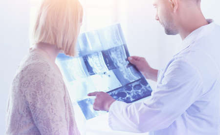 Handsome doctor is talking with young female patient and makingの写真素材
