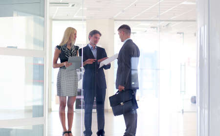Business woman standing with her staff in background at modern officeの写真素材