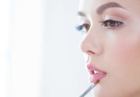 Beautiful girl with cosmetic powder brush for make up. Makeup. Make-up applying for perfect skinの写真素材