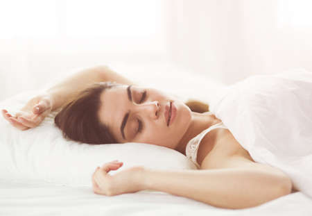 Pretty woman lying down on her bed at homeの写真素材