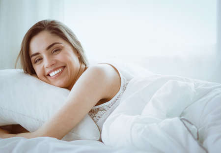 Pretty woman lying down on her bed at homeの写真素材