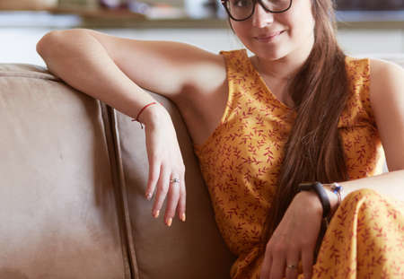Portrait of smiling woman sitting on sofa. Casual style indoor shootの写真素材