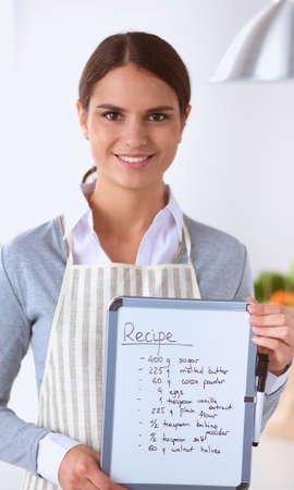 Woman in the kitchen at home, standing near desk with folderの写真素材