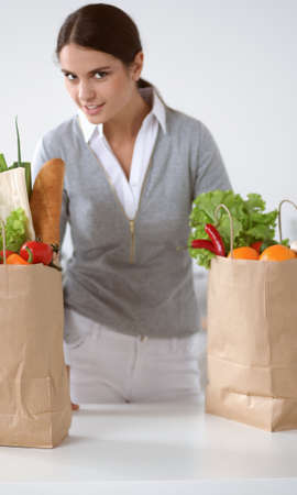 Young woman holding grocery shopping bag with vegetables Standing in the kitchenの写真素材
