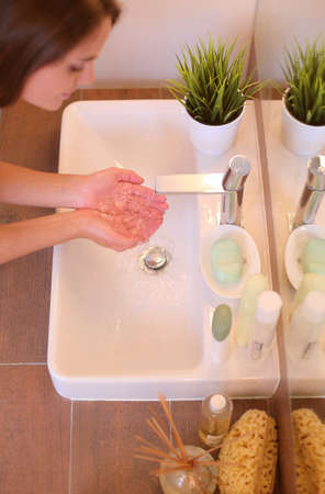 Young woman washing her face with clean water in bathroomの写真素材