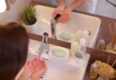 Young woman washing her face with clean water in bathroomの写真素材