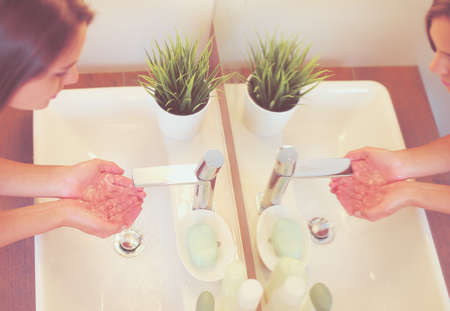 Young woman washing her face with clean water in bathroomの写真素材
