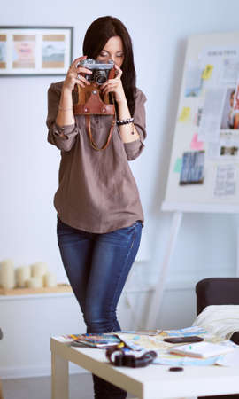 Young woman watching footage on film, standing near windowの写真素材