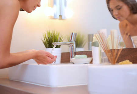 Young woman washing her face with clean water in bathroomの写真素材