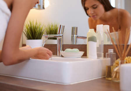Young woman washing her face with clean water in bathroomの写真素材