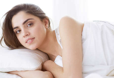 Pretty woman lying down on her bed at homeの写真素材