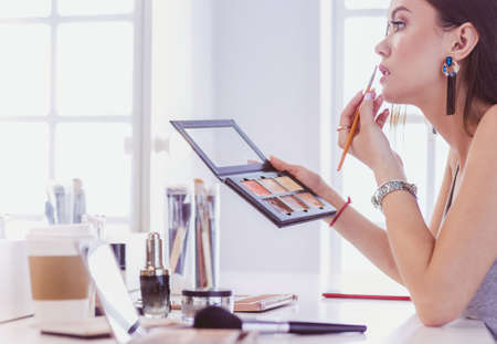Brunette woman applying make up for a evening date in front of a mirrorの写真素材