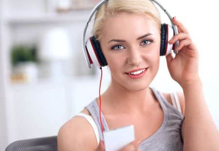 Young beautiful woman at home sitting on sofa and listening musicの写真素材