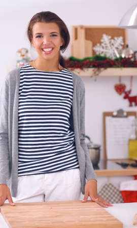 Smiling young woman in the kitchen, isolated on christmas backgroundの写真素材
