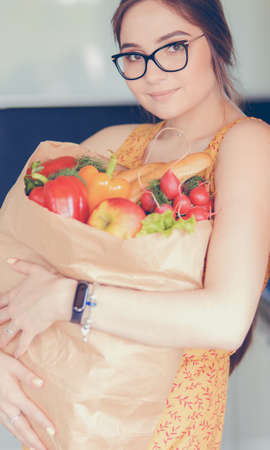 Young woman holding grocery shopping bag with vegetablesの写真素材