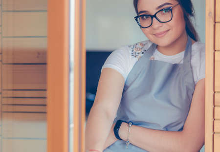 Young woman standing near desk in the kitchenの写真素材