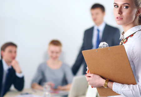 Portrait of a young woman working at office standing with folderの写真素材