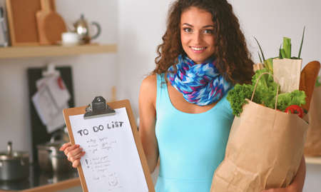 Young woman holding grocery shopping bag with vegetables Standing in the kitchen.の写真素材