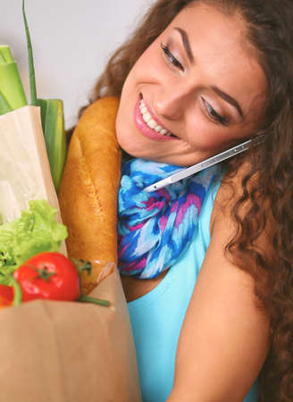 Young woman holding grocery shopping bag with vegetables Standing in the kitchen.の写真素材